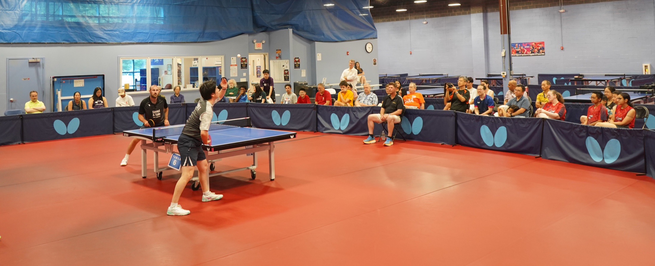 Wide view of the Princeton Pong club floor with multiple tables and a match underway