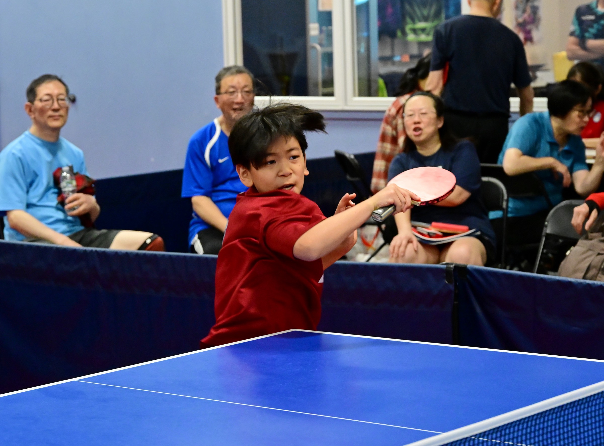 A young Princeton Pong player drives through a forehand as spectators look on