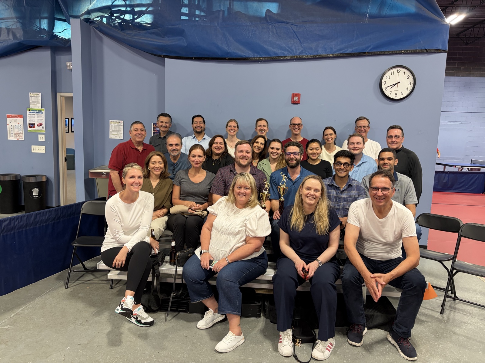 A large corporate group posing with a tournament trophy at Princeton Pong