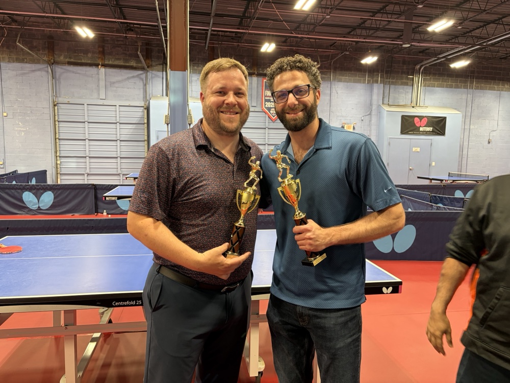 Two corporate tournament winners holding trophies at Princeton Pong