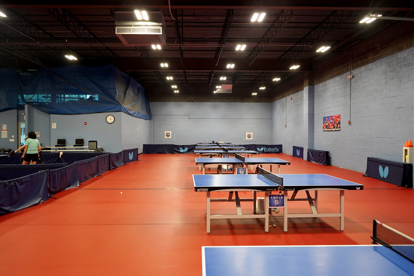 Rows of numbered Butterfly tournament tables on the red court floor