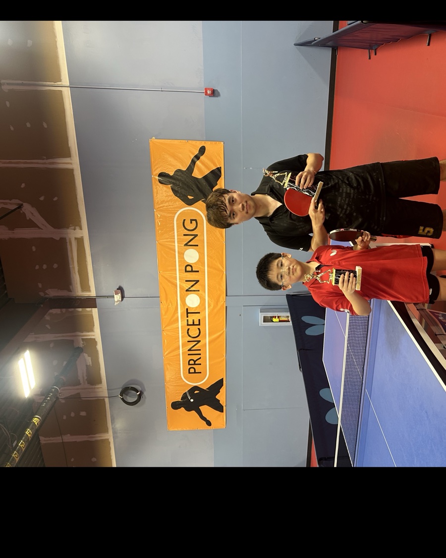A junior and adult player holding trophies at Princeton Pong